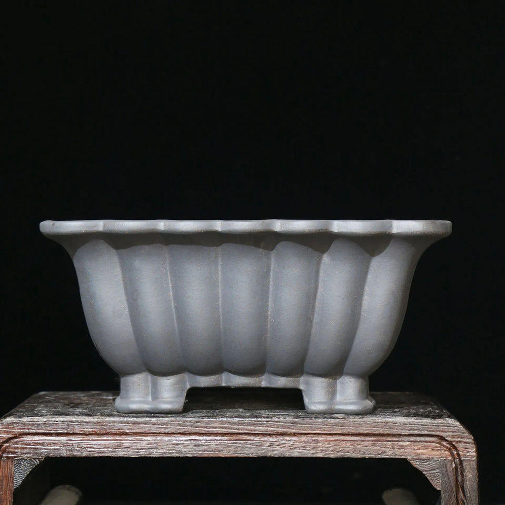 Square purple sand ceramic bonsai pot with du xiliang glaze on a desktop.