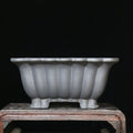Square purple sand ceramic bonsai pot with du xiliang glaze on a desktop.