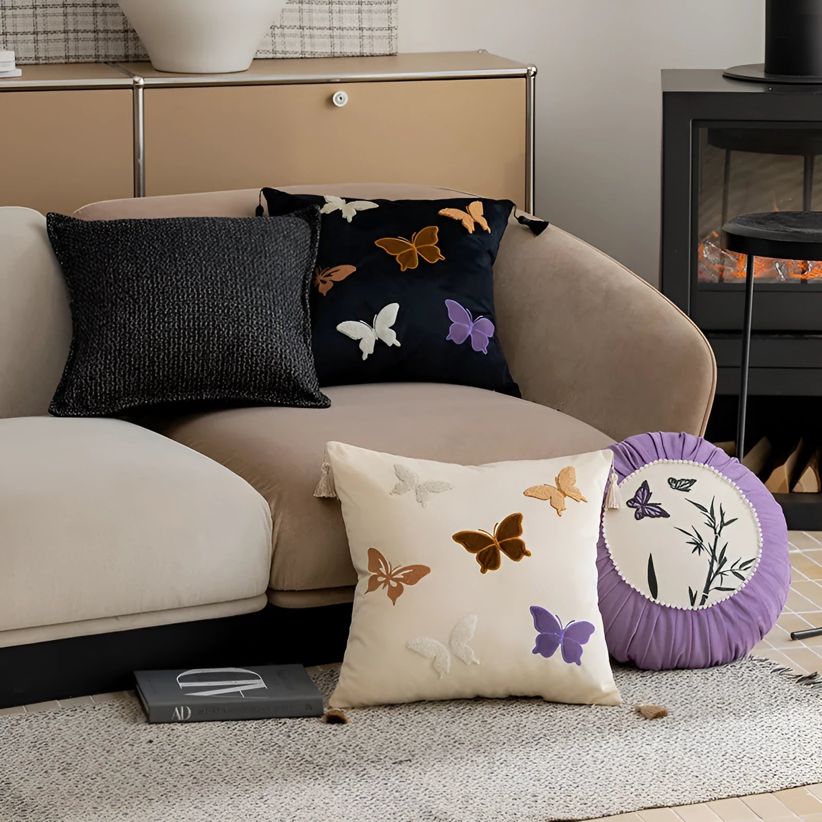 Square beige cushion with butterfly embroidery on a sofa, showing purple and black colour options.