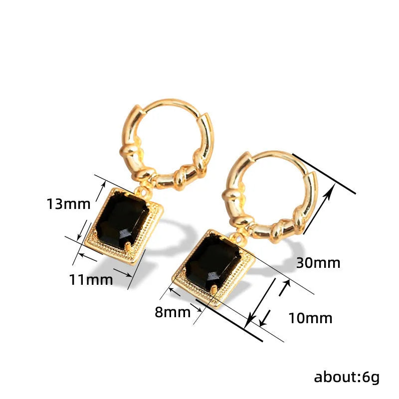 A pair of black geometric quadrilateral earrings with zircon stones on copper settings, shown against a plain background.