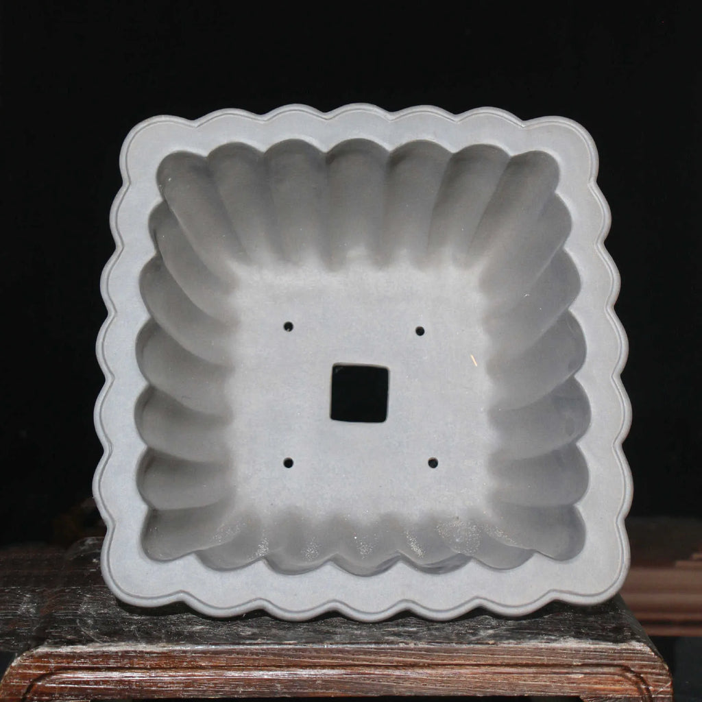 Square purple sand ceramic bonsai pot with du xiliang glaze on a desktop.