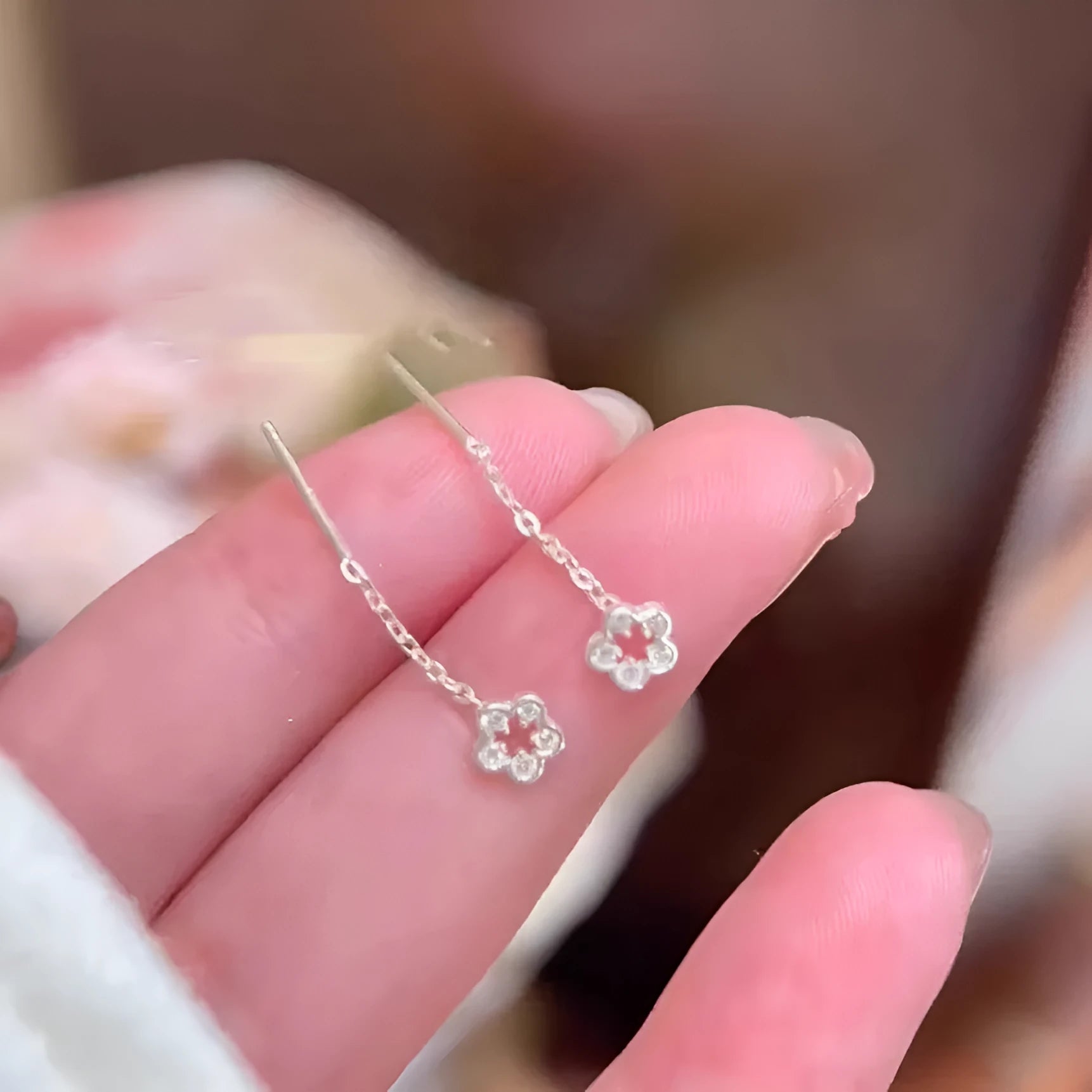 A pair of silver-coloured hollow flower stud earrings with petal details on sterling silver posts.