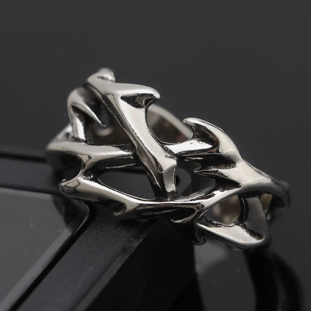 Copper geometric ring with thorn and flower design on a finger, showing adjustable opening.