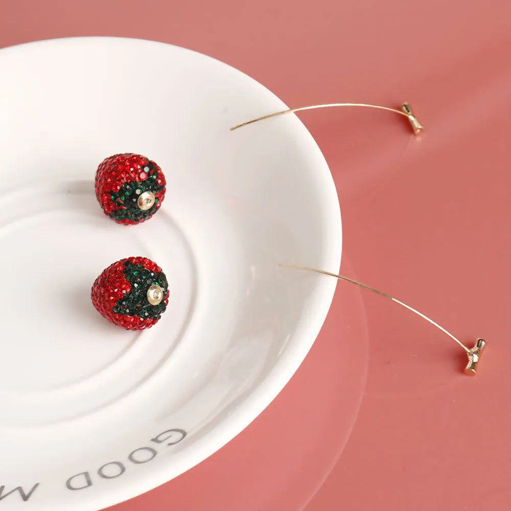 A pair of red geometric strawberry stud earrings with a faceted surface and butterfly clutch fastenings.