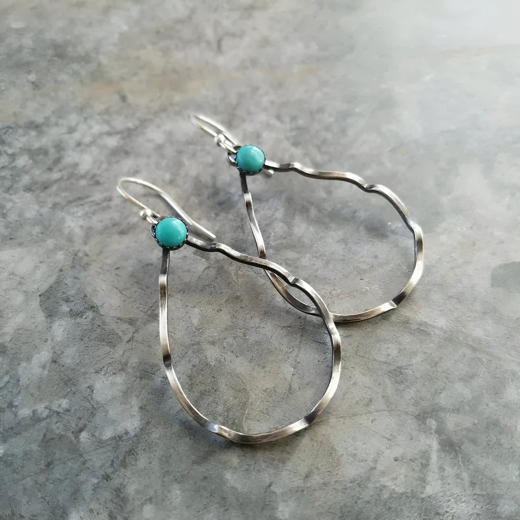 A pair of antique silver geometric circle earrings with a turquoise blue centre, showing bohemian vintage style.