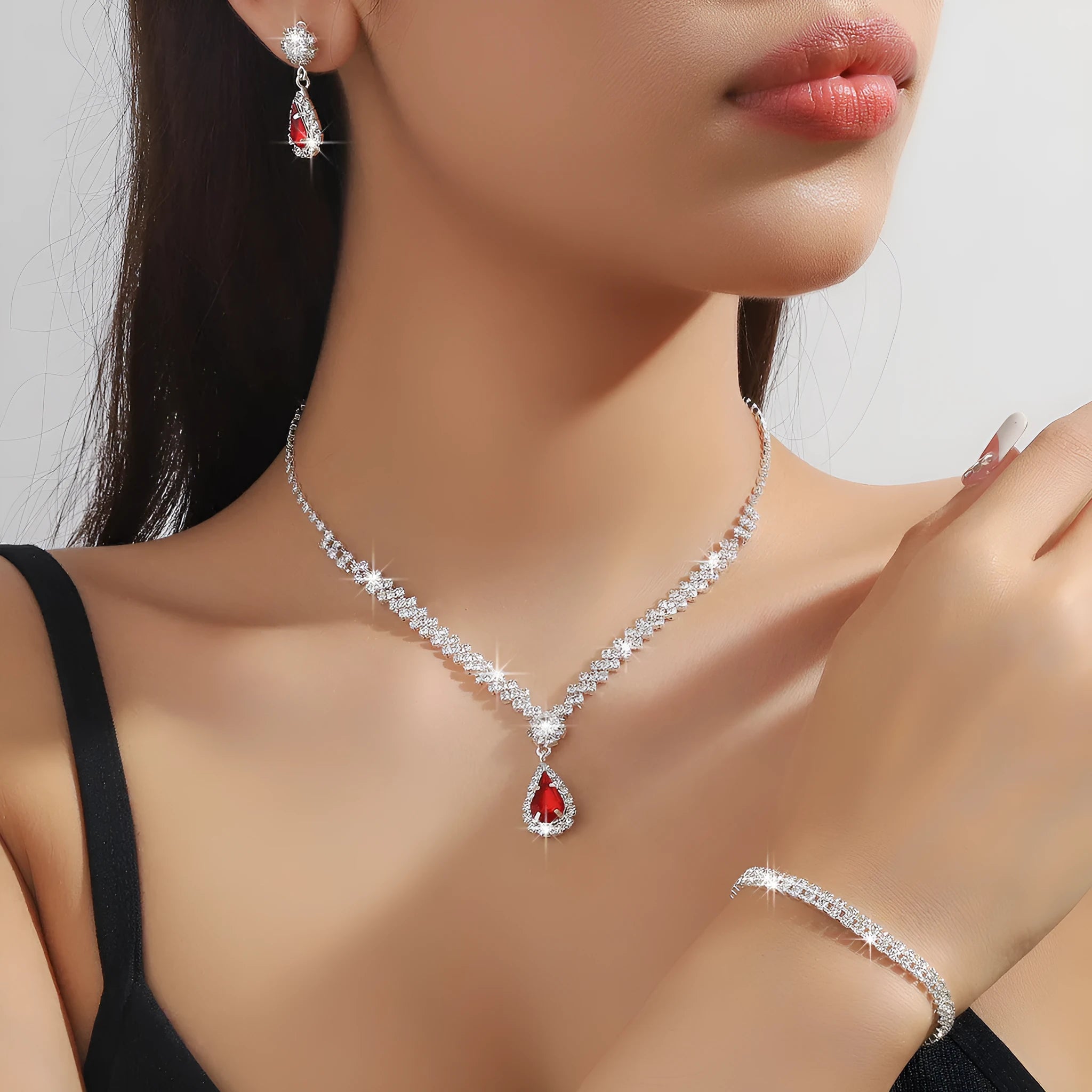 Women's blue claw chain necklace and drop rhinestone earrings set on white background.