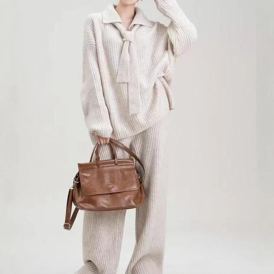 Beige women's knitted sweater suit set with collage stitch detail on top and trousers on a hanger.