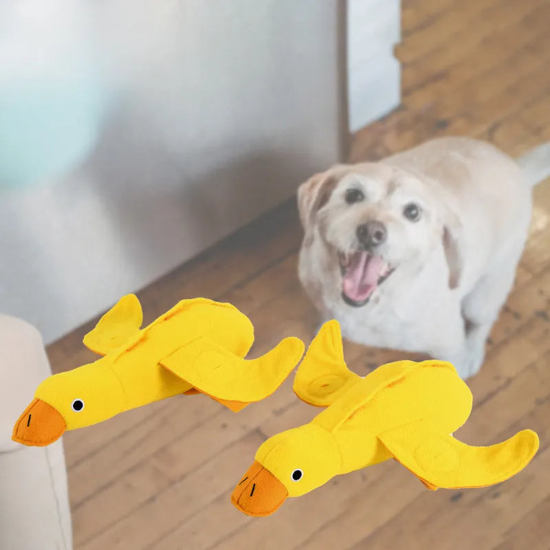 Yellow plush duck dog training toy with a squeaker and treat compartments on a white background.