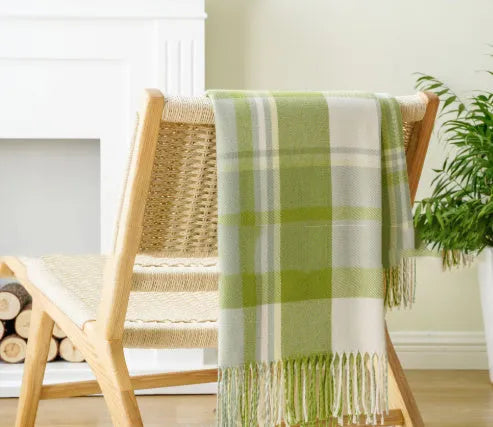 Acrylic chenille plaid throw blanket with tassel trim in gray and white geometric pattern on sofa