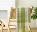 Acrylic chenille plaid throw blanket with tassel trim in gray and white geometric pattern on sofa