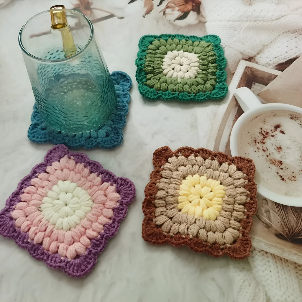 Hand crocheted wool cup coaster in Grandmother Lattice pattern, colour options include Emerald, Sea Salt Blue, Dream Purple, and Fog Brown.