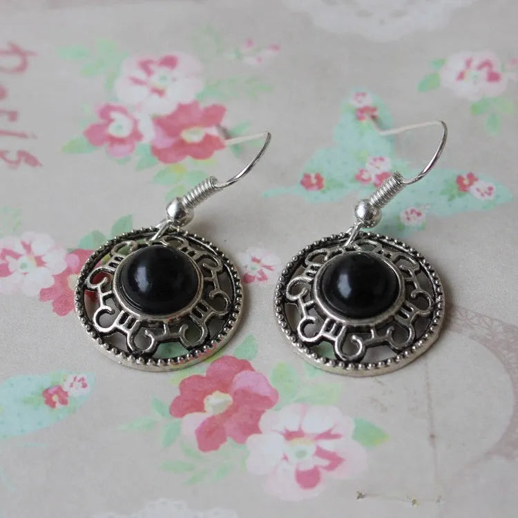 A pair of handmade geometric flower disk earrings in Tibetan silver and turquoise with ethnic patterns.