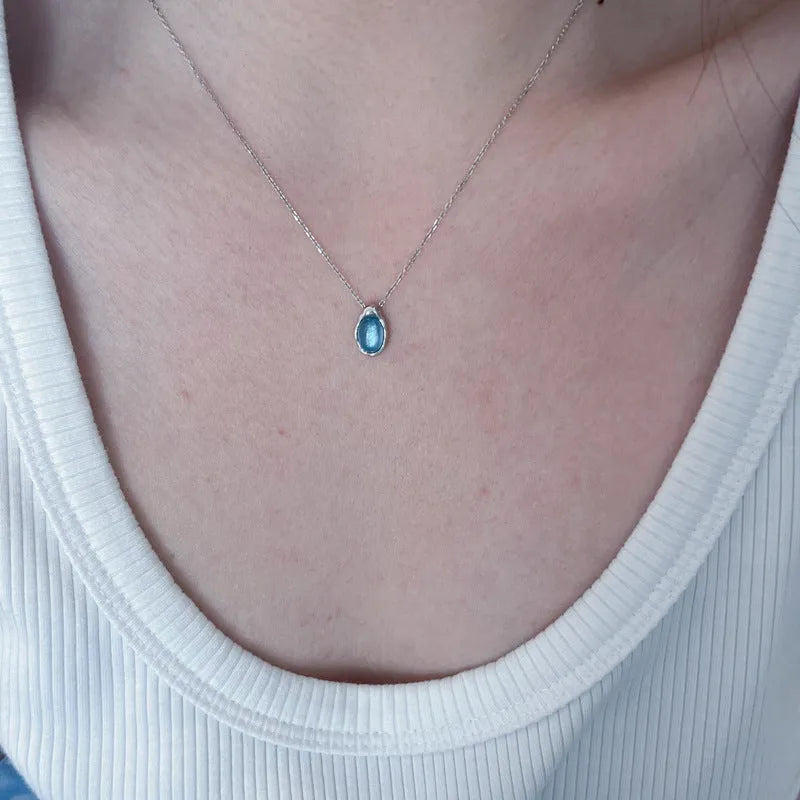 Navy blue water drop pendant necklace on a model, showing the adjustable cross chain and geometric copper design.