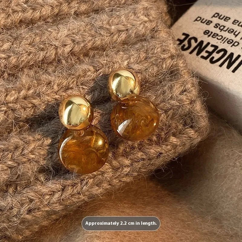 Three pairs of geometric tassel earrings in Maillard, amber, and tigereye colours on a white background