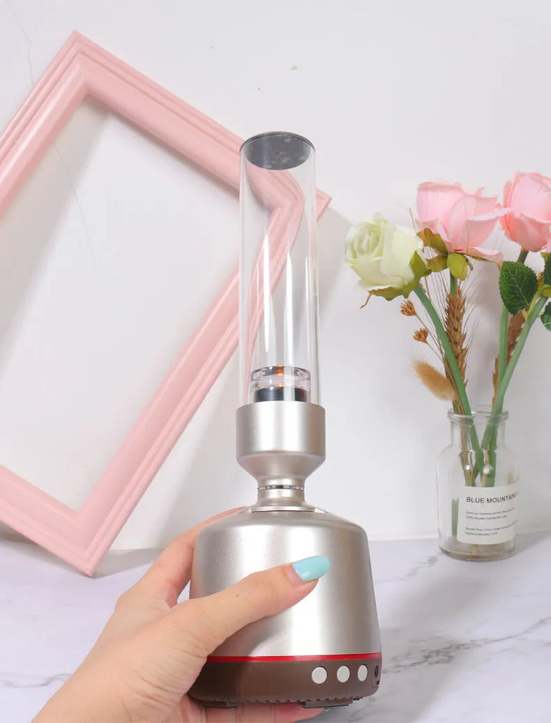 White silver cylindrical Candlelight Bluetooth Speaker Night Light showing warm internal glow and push-button controls.