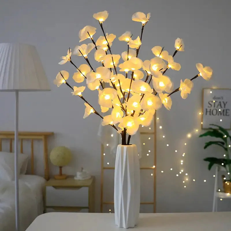 Pink LED phalaenopsis orchid branch light, 65cm tall, on a wooden surface emitting a warm glow.