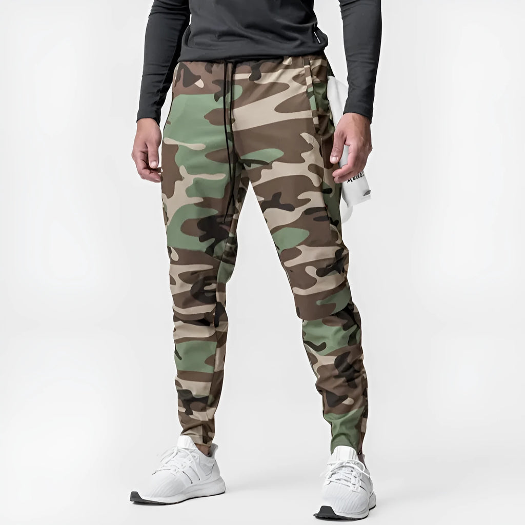 Man wearing dark grey loose-fit fitness trousers with tied ankles, made of quick-dry polyester blend fabric.