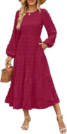 A woman wearing a beige high waist long sleeve dress with ruffled sleeves, a round neck, and a solid colour design.