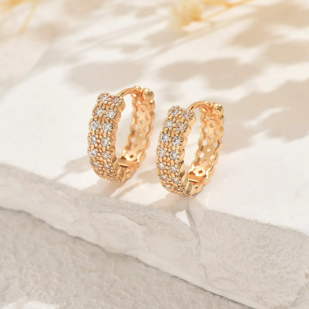 A pair of polished copper geometric ear studs featuring a thin ring with a small central dot on a white background.