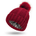 Women's black knit beanie hat with a white faux fur pom pom and visible satin lining.