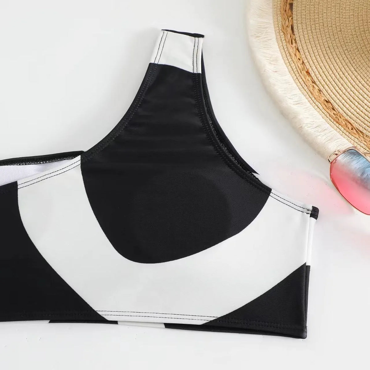 Black one-shoulder two-piece swimsuit with briefs and wrap skirt, sizes S-XL, nylon fabric.