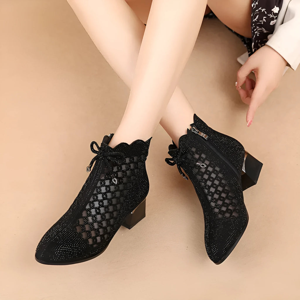 Black women's ankle boots with cutout mesh panels, mid heel, side zipper, and rhinestone sequin details