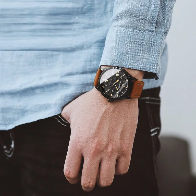Men's automatic mechanical watch with leather strap on wrist, showing classic dial options.