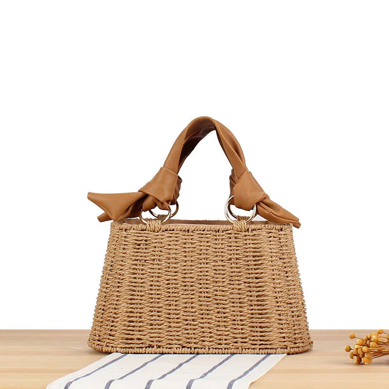 Portable woven straw bag in beige with hard trapezoid shape and double shoulder straps for seaside vacation daily use.