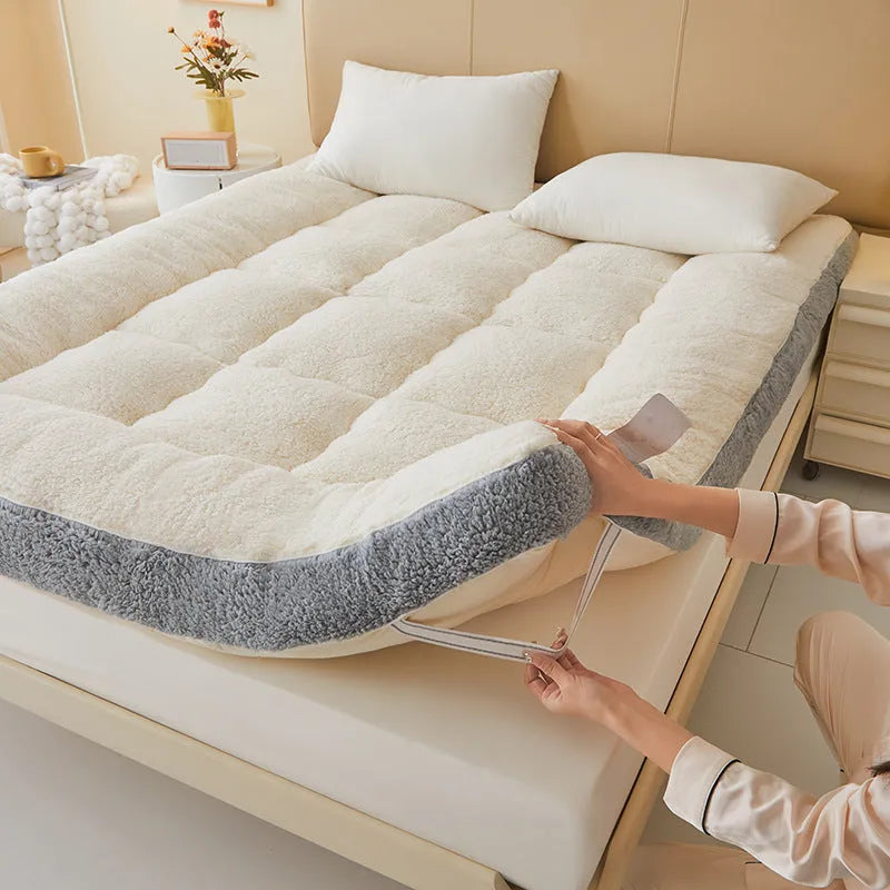 Lambswool mattress cushion with velvet cover in grey and white edge, on a bed