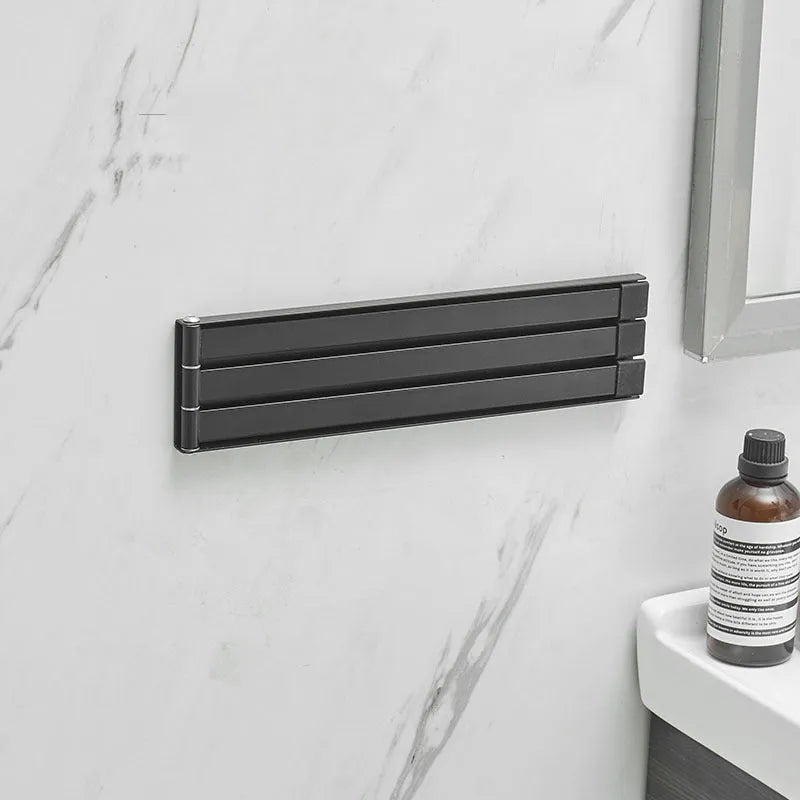 Black folding towel rack mounted on bathroom wall with adhesive installation