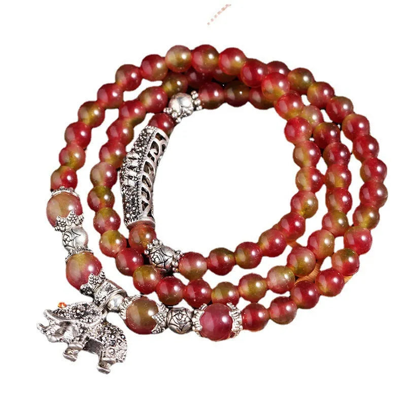 A handmade bracelet with geometrically cut watermelon crystal beads and a red Chinese knot closure on a white background.