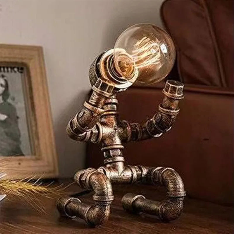 Industrial retro style iron pipe table lamp with water pipe robot design on a desk.