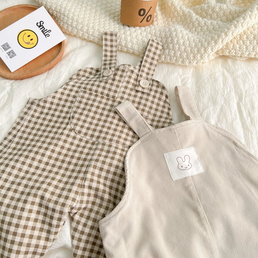 Unisex corduroy suspender overalls in creamy-white or brown plaid, with large pockets and double-breasted closure, for spring and autumn.