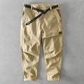 Man wearing khaki coloured casual cotton overalls with an elastic mid-waist and loose trouser legs.