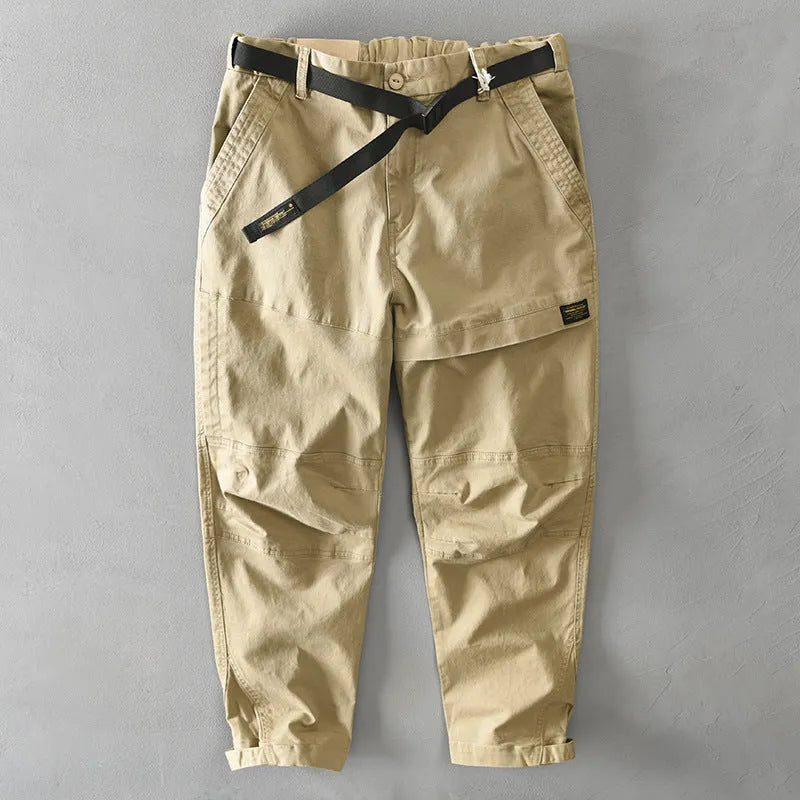 Man wearing khaki coloured casual cotton overalls with an elastic mid-waist and loose trouser legs.