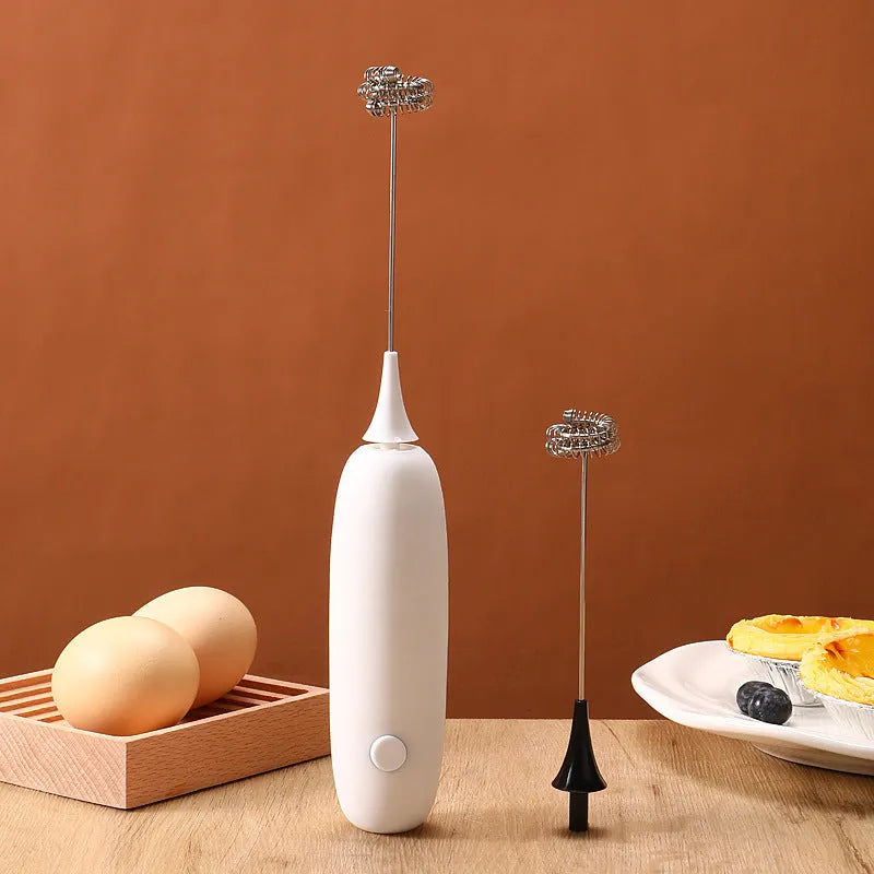A handheld electric milk frother in black and white colours on a kitchen counter.