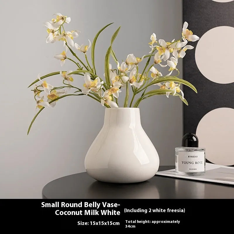 Modern round belly ceramic vase with coloured glaze, shown in black and white, some with artificial flowers.