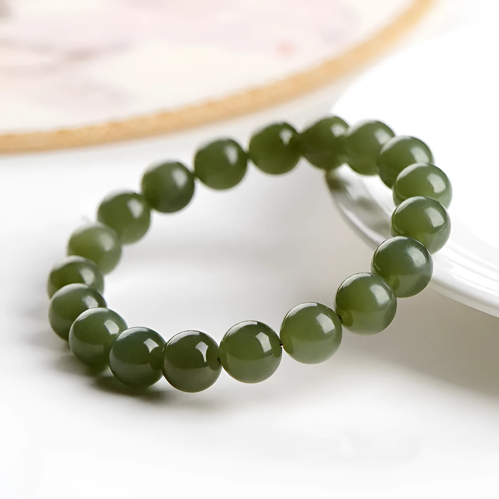 A polished Hetian jade bead bracelet in deep clear water colour on a wrist.