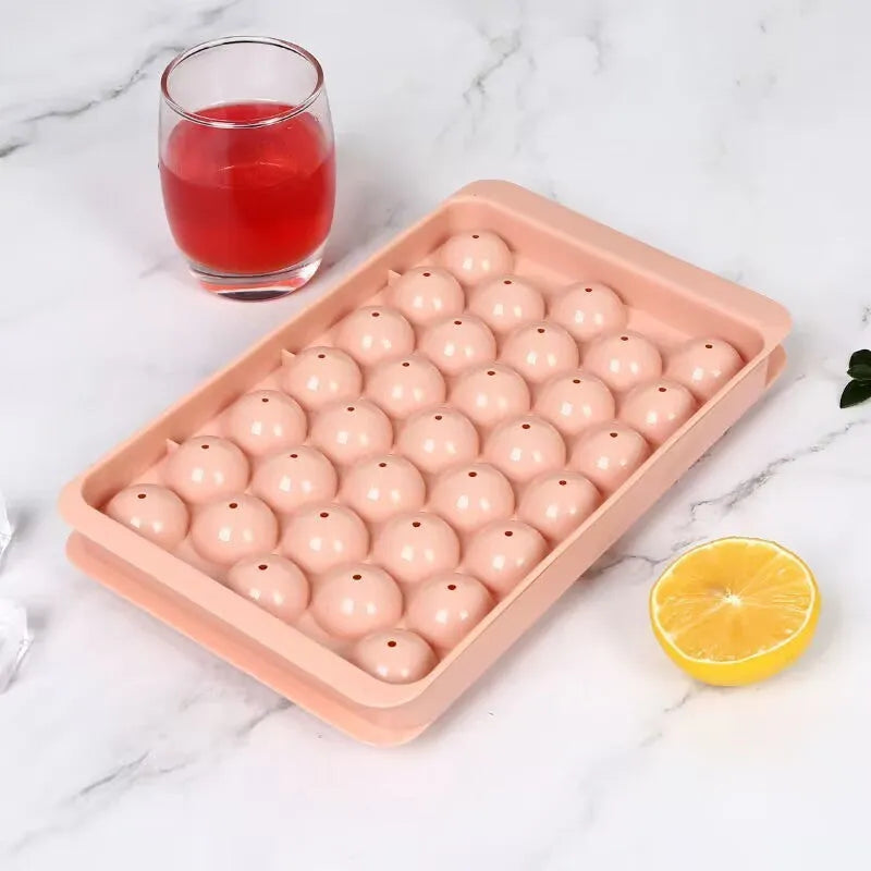 Blue lidded silicone ice cube tray making 33 round ice spheres on a kitchen counter.