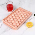 Blue lidded silicone ice cube tray making 33 round ice spheres on a kitchen counter.