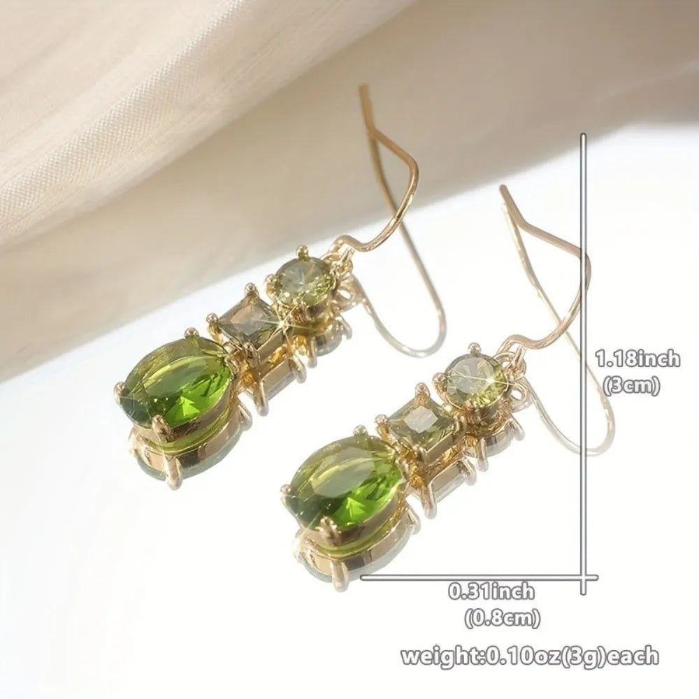Green geometric copper earrings with a quadrilateral shape on a plain background.