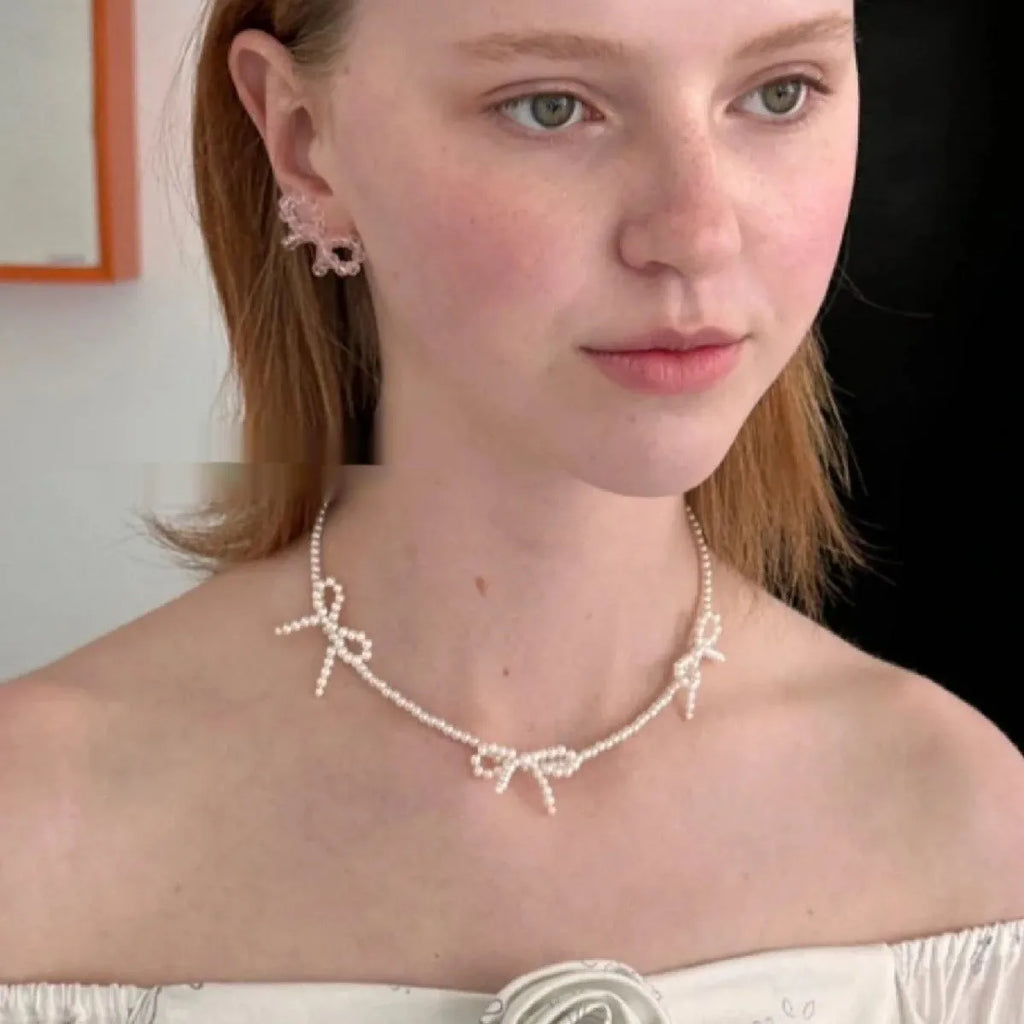 White bow pearl necklace with geometric clasp on woman at clavicle length