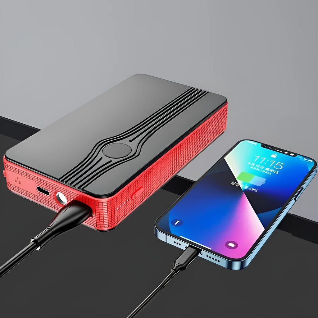 Red K4-E portable car jump starter and power bank unit with USB cable on a table.