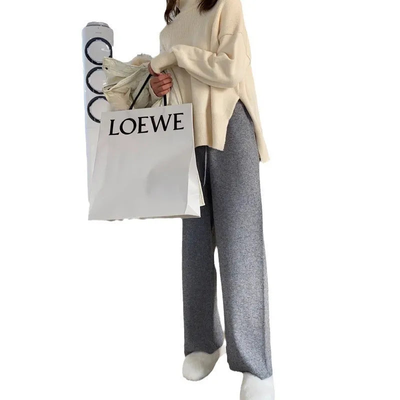Women's cream white high-waisted wide-leg knitted trousers with a straight leg and drooping hem.