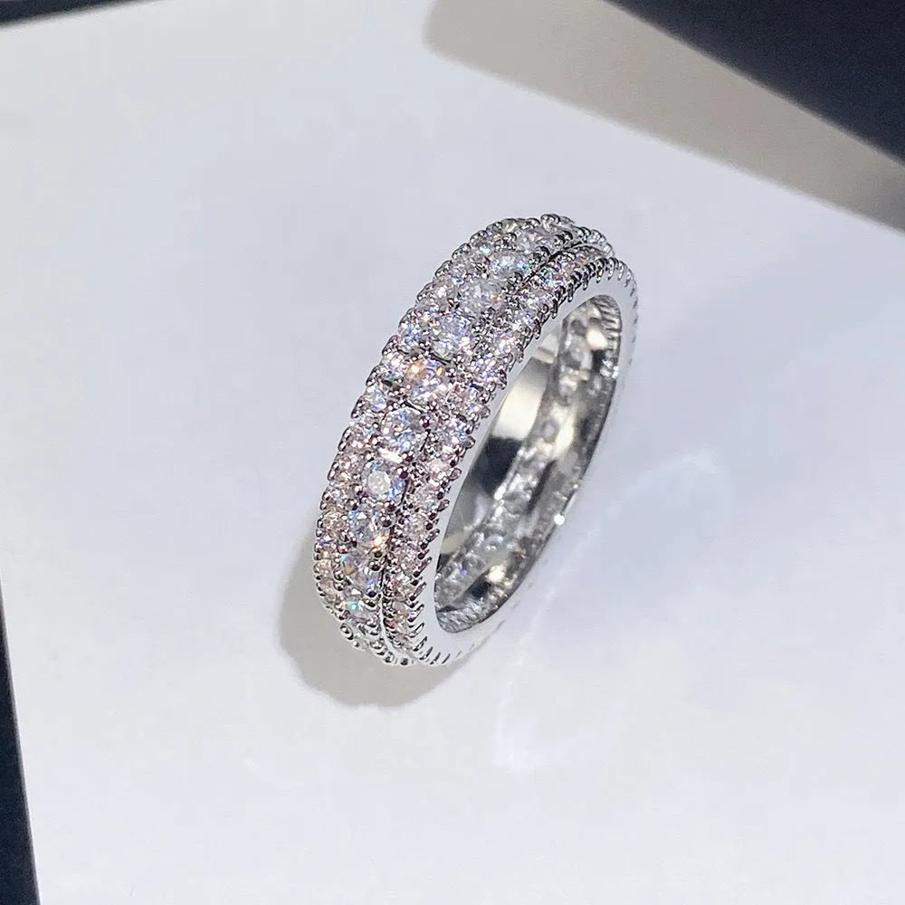 Geometric copper ring with a triangular zircon stone, shown in white gold finish on a finger.