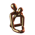Modern loving couple resin statue in milky white or gold colour on a desk.