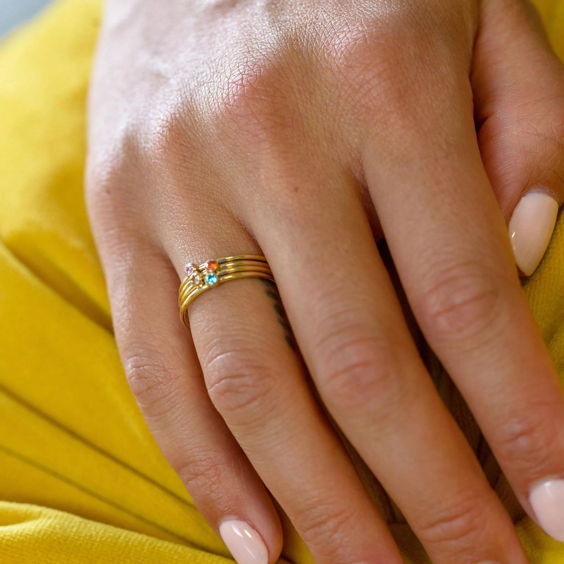A geometric titanium steel ring with a December birthstone and gold-coloured handle on a plain background.
