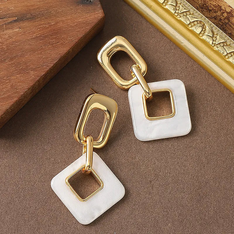 A pair of hollow geometric square copper earrings with chamfered corners on a white background.