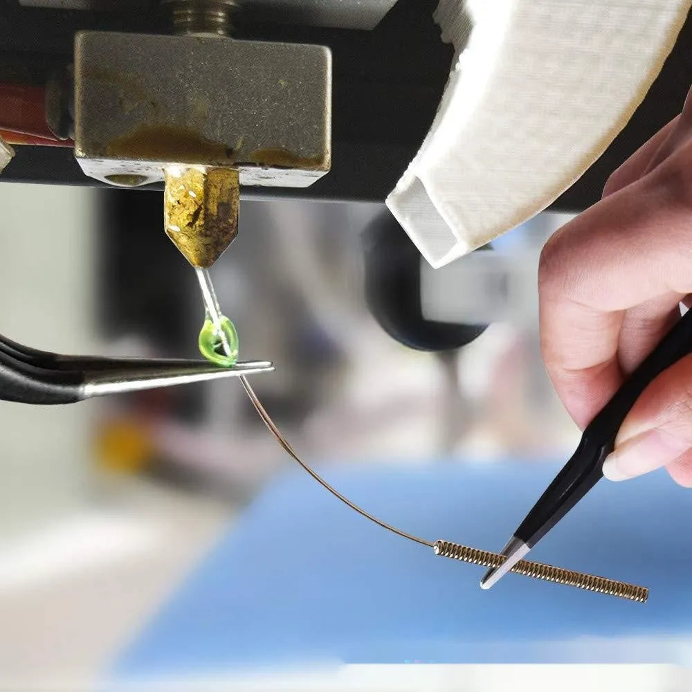 Brass MK8 3D printer nozzle and stainless steel cleaning pin set on a white background.