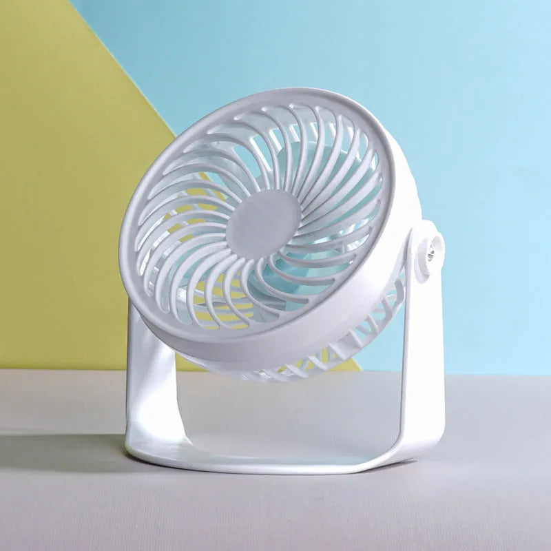 Small white USB desk fan with clip base and three blades on a wooden desk.